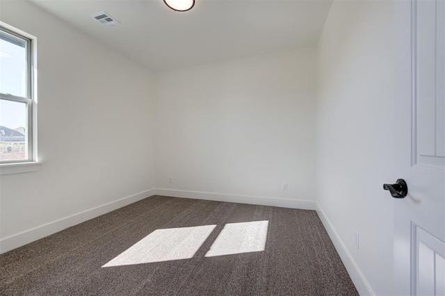 spare room with plenty of natural light and dark carpet