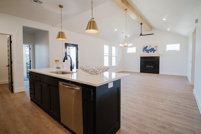 kitchen featuring pendant lighting, sink, lofted ceiling with beams, stainless steel dishwasher, and a center island with sink