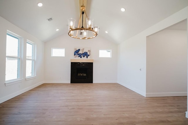 unfurnished living room with an inviting chandelier, a fireplace, hardwood / wood-style flooring, and high vaulted ceiling