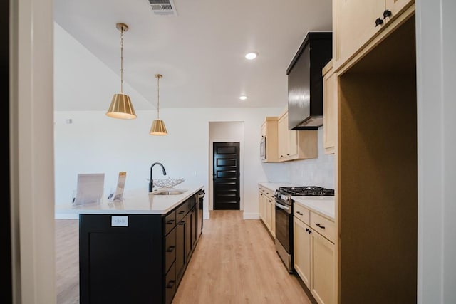 kitchen featuring tasteful backsplash, pendant lighting, sink, appliances with stainless steel finishes, and an island with sink