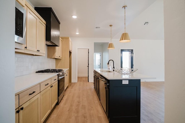 kitchen with decorative light fixtures, stainless steel appliances, sink, backsplash, and a kitchen island with sink