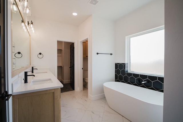 bathroom with toilet, a tub to relax in, and vanity