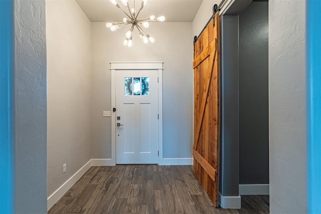 entryway featuring dark wood-type flooring, a chandelier, and a barn door