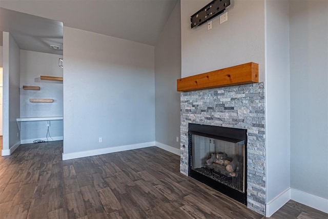 unfurnished living room featuring dark hardwood / wood-style flooring and a stone fireplace