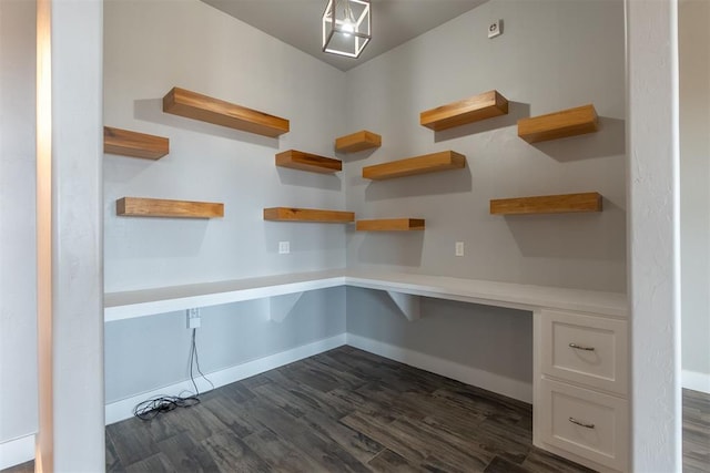 unfurnished office featuring dark hardwood / wood-style flooring and built in desk