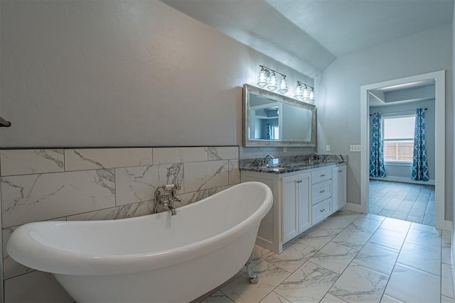 bathroom featuring lofted ceiling, vanity, and a bath