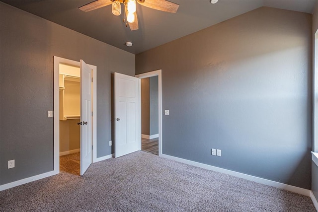 unfurnished bedroom with ceiling fan, lofted ceiling, carpet flooring, a spacious closet, and a closet