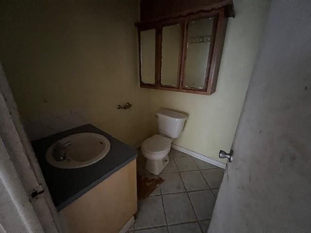 bathroom with toilet, vanity, and tile patterned flooring