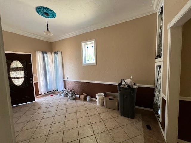 entrance foyer featuring light tile patterned floors and crown molding