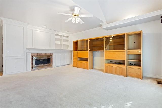 unfurnished living room featuring ceiling fan, ornamental molding, light carpet, and a fireplace