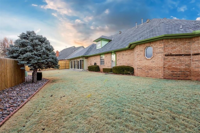 back house at dusk featuring a lawn