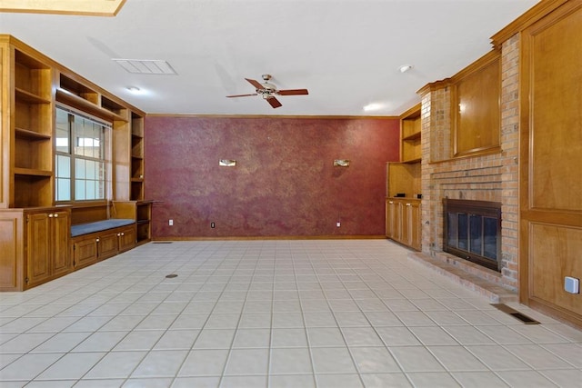 unfurnished living room featuring a brick fireplace, light tile patterned floors, built in features, and ceiling fan