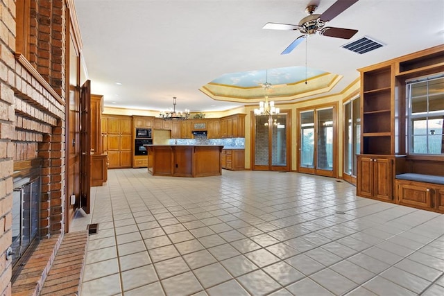 kitchen featuring hanging light fixtures, a center island, a fireplace, black appliances, and a raised ceiling