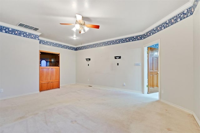 spare room with ceiling fan, ornamental molding, and light carpet