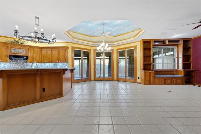 kitchen featuring crown molding, a tray ceiling, sink, and hanging light fixtures