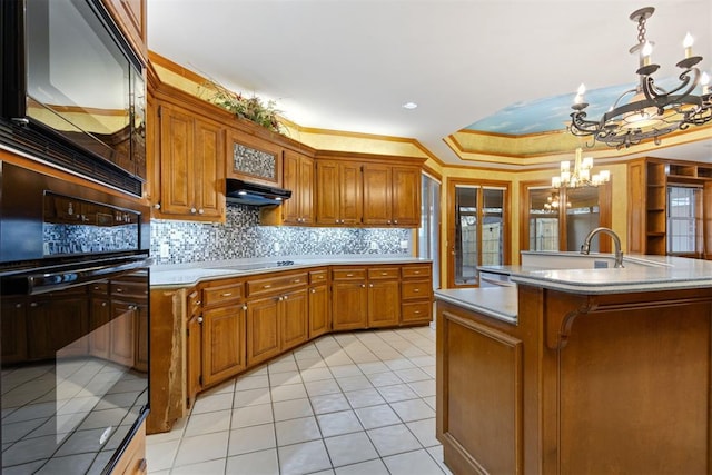 kitchen featuring crown molding, an inviting chandelier, hanging light fixtures, an island with sink, and electric stovetop