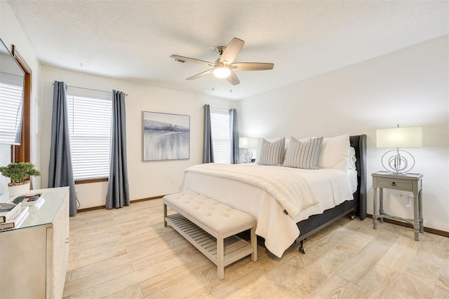 bedroom with a textured ceiling, light hardwood / wood-style flooring, and ceiling fan