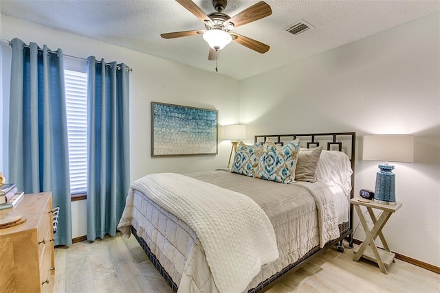 bedroom with light wood-type flooring, ceiling fan, and a textured ceiling