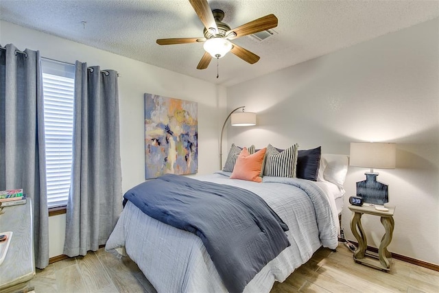 bedroom with light hardwood / wood-style floors, a textured ceiling, and ceiling fan