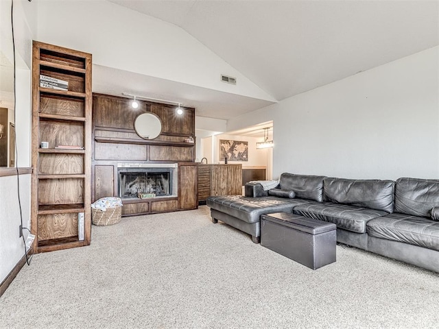 carpeted living room featuring a large fireplace and vaulted ceiling