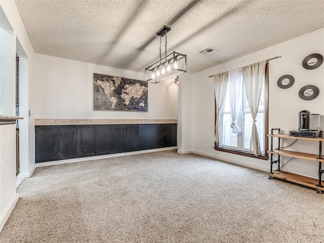 interior space with visible vents, a textured ceiling, baseboards, and carpet floors