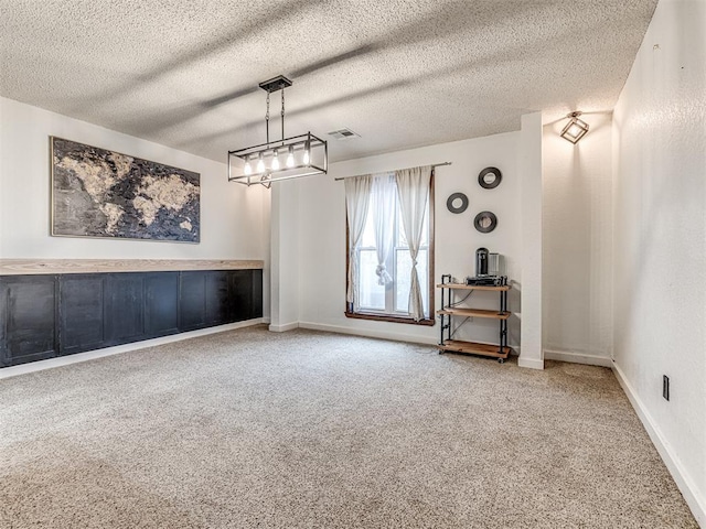 unfurnished room with carpet flooring, baseboards, visible vents, and a textured ceiling