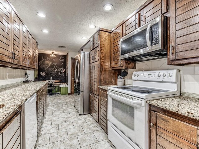 kitchen featuring tasteful backsplash, a textured ceiling, recessed lighting, appliances with stainless steel finishes, and brown cabinetry