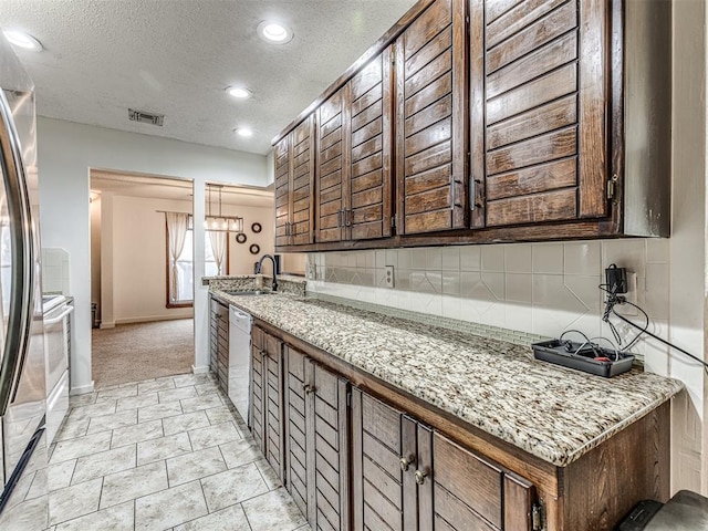 kitchen featuring tasteful backsplash, visible vents, white dishwasher, a textured ceiling, and a sink