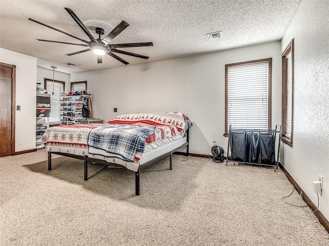 bedroom featuring visible vents, a textured ceiling, carpet floors, baseboards, and ceiling fan