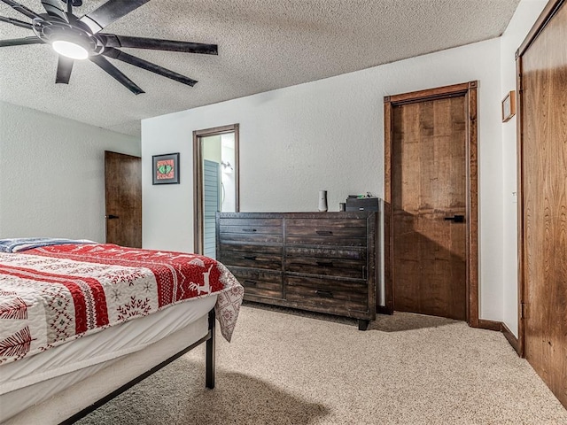 bedroom with ceiling fan, a textured wall, carpet floors, and a textured ceiling