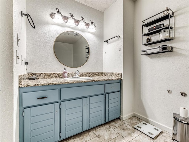 bathroom featuring vanity, baseboards, and a textured wall