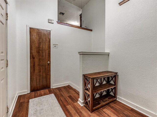 entrance foyer with a textured wall, baseboards, and wood finished floors