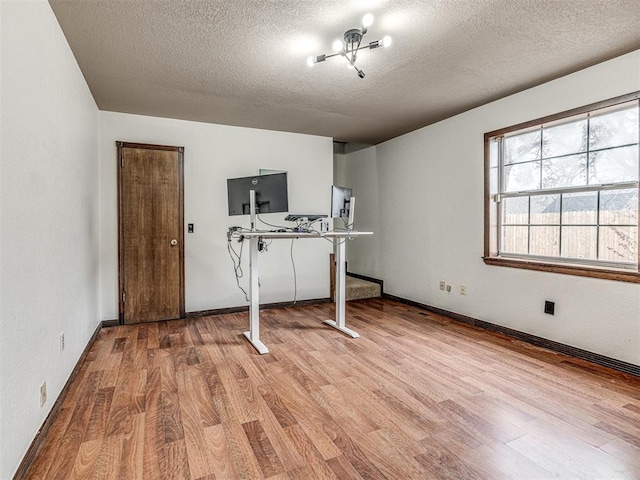 interior space featuring baseboards, a textured ceiling, and wood finished floors