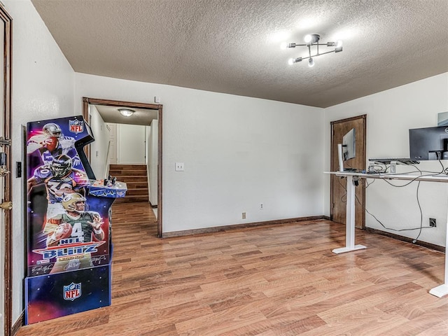 interior space with light wood-style floors, baseboards, and a textured ceiling