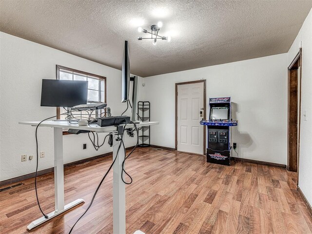 exercise room with visible vents, a textured ceiling, baseboards, and wood finished floors