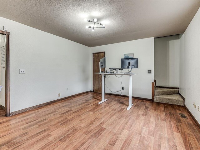 interior space with visible vents, baseboards, stairway, light wood-style floors, and a textured ceiling