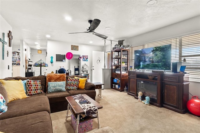 carpeted living room with ceiling fan and a textured ceiling