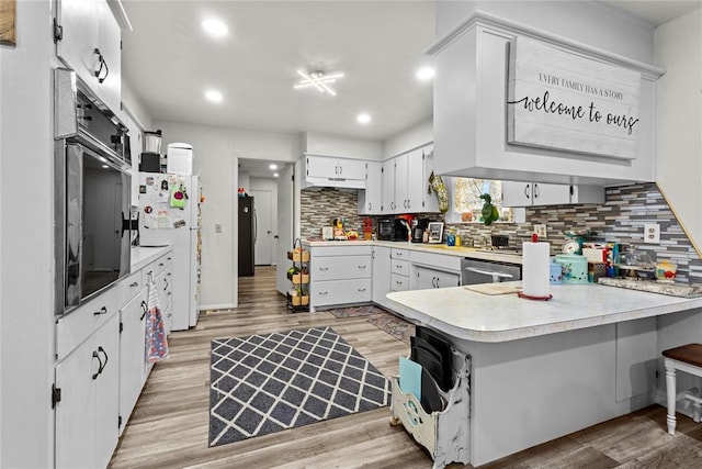 kitchen featuring white cabinets, white refrigerator, tasteful backsplash, and light wood-type flooring