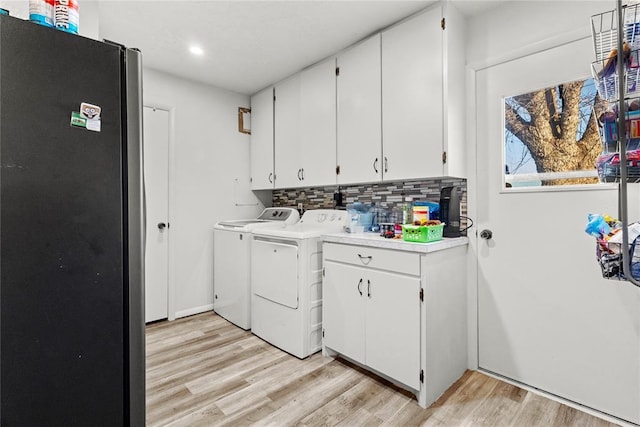 laundry room featuring light wood-type flooring, independent washer and dryer, and cabinets