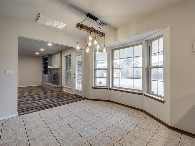 empty room with light tile patterned floors and a large fireplace