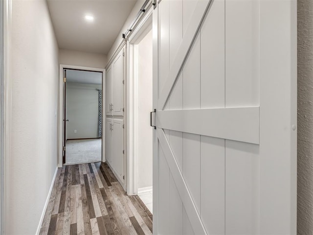 hall with light hardwood / wood-style floors and a barn door