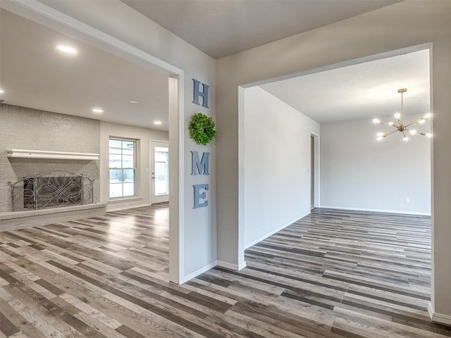 interior space featuring hardwood / wood-style flooring, a brick fireplace, and a notable chandelier