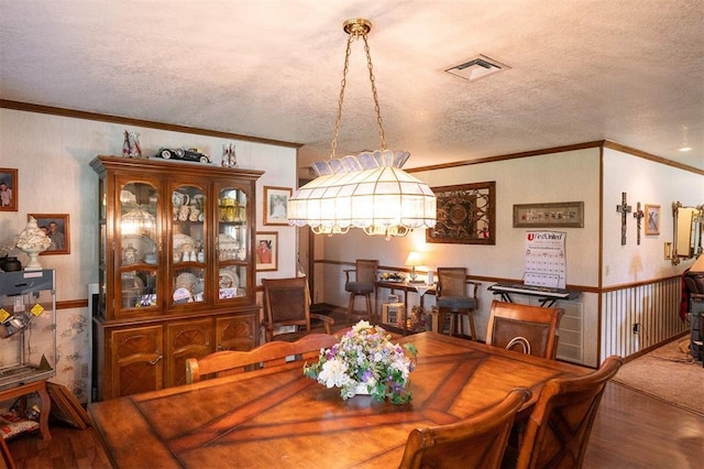 dining area with crown molding, a textured ceiling, and hardwood / wood-style flooring