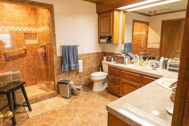 bathroom with toilet, vanity, tile patterned flooring, tile walls, and a tile shower