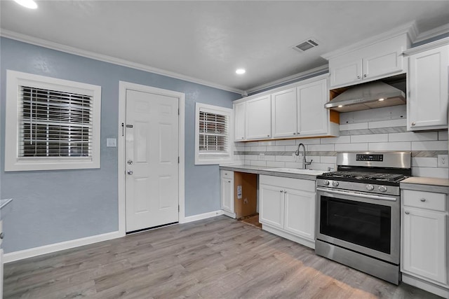 kitchen with backsplash, sink, crown molding, white cabinetry, and stainless steel gas range