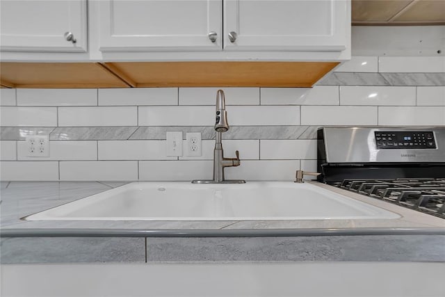 interior details with white cabinetry, stainless steel gas stove, and sink