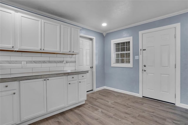 kitchen featuring white cabinetry, decorative backsplash, ornamental molding, and light hardwood / wood-style floors