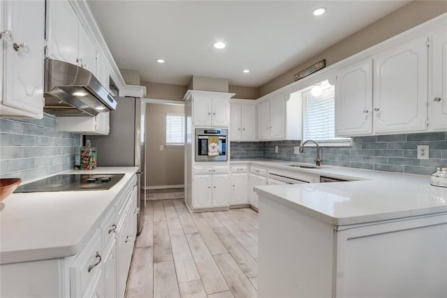 kitchen featuring sink, stainless steel oven, kitchen peninsula, white cabinets, and backsplash