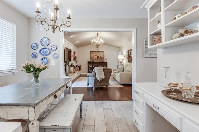 dining room featuring an inviting chandelier, vaulted ceiling, and light hardwood / wood-style flooring