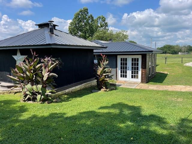 back of property featuring a lawn and french doors